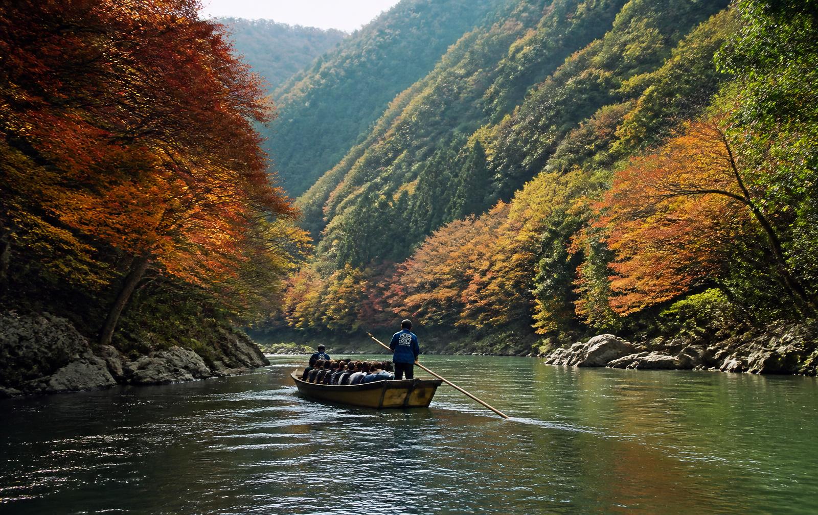 A traditional wooden boat on the Hozugawa river through an autumn gorge near Kameoka