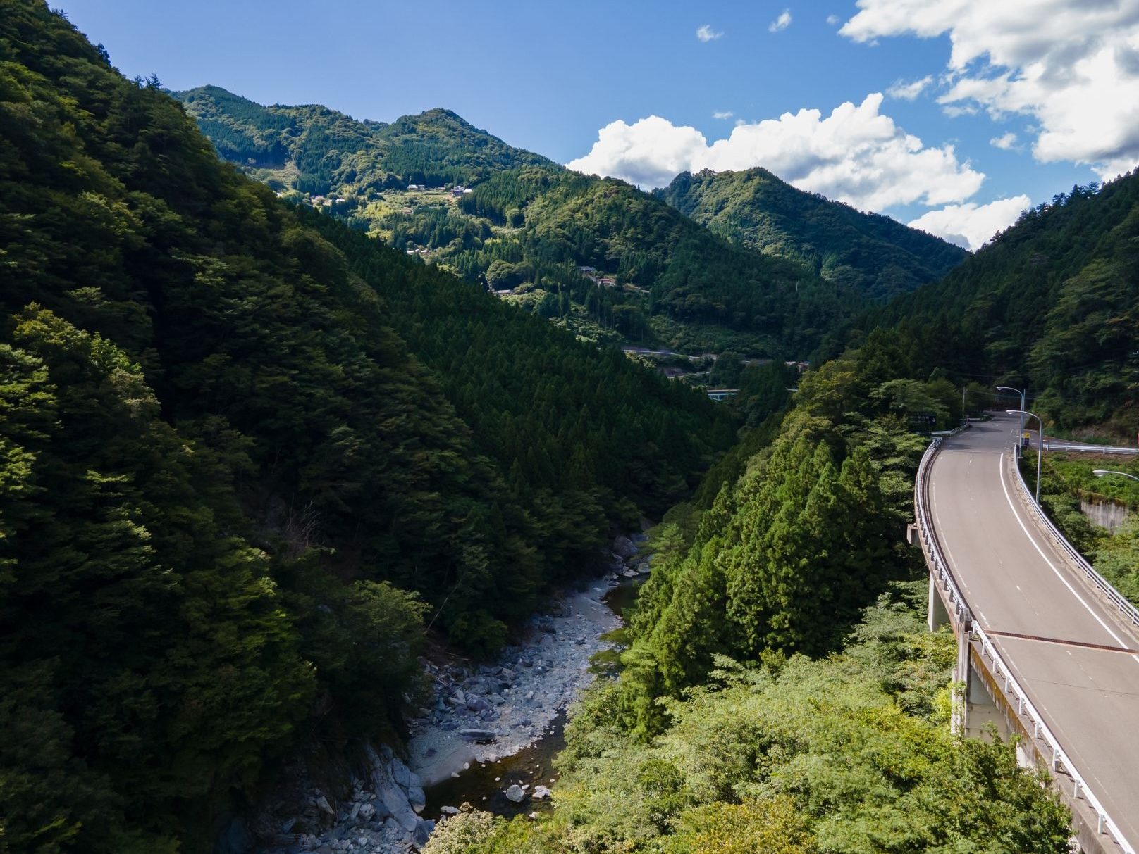 A winding mountain road following the river through steep forested slopes