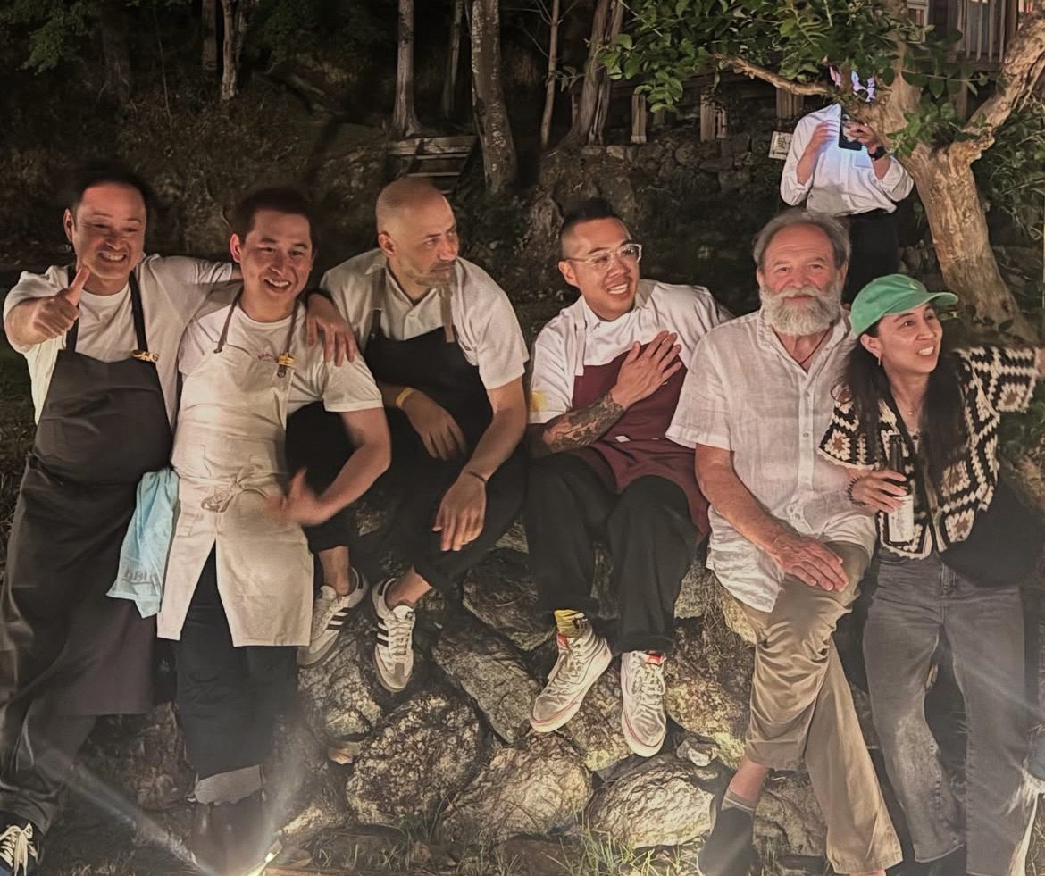 Six guests in aprons sitting together on a stone wall in the evening
