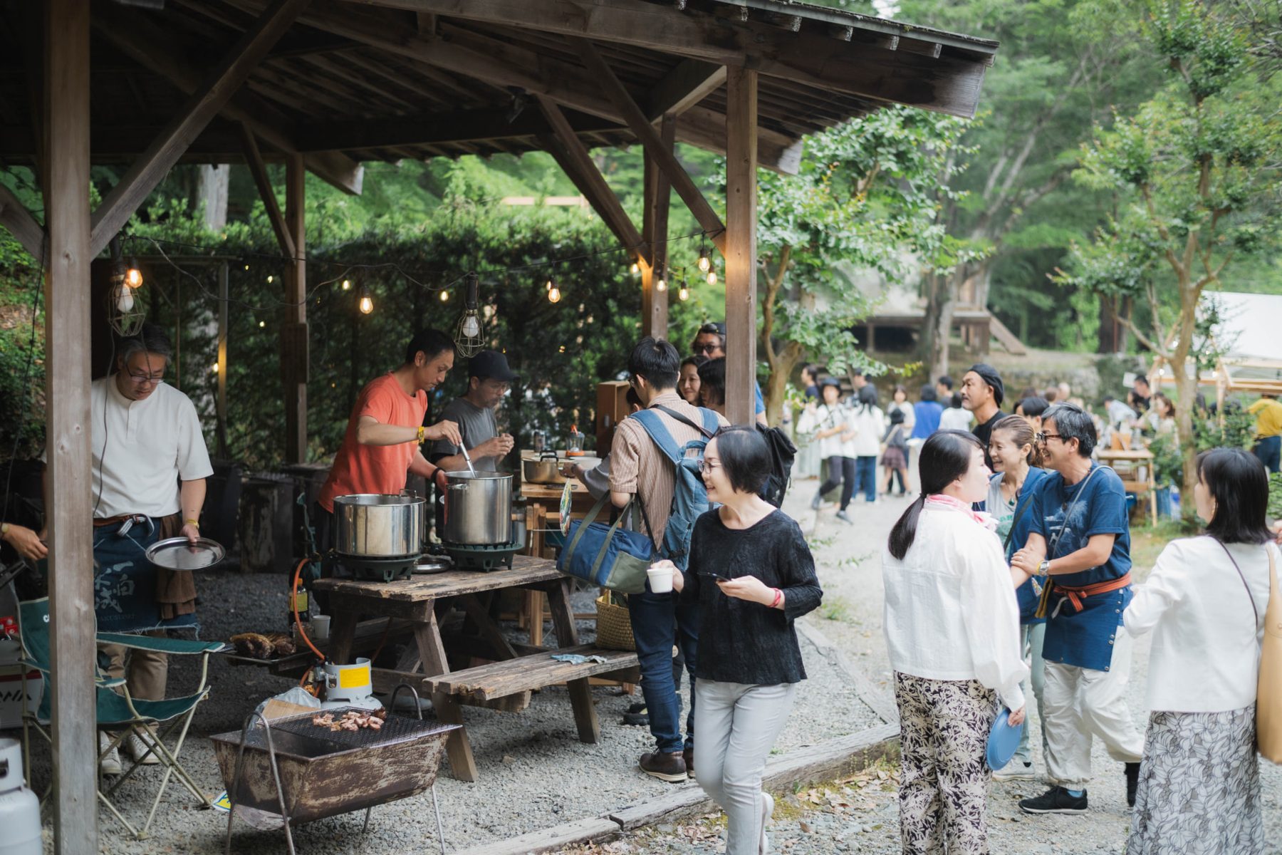 Guests gathered around an outdoor food stall in the forest