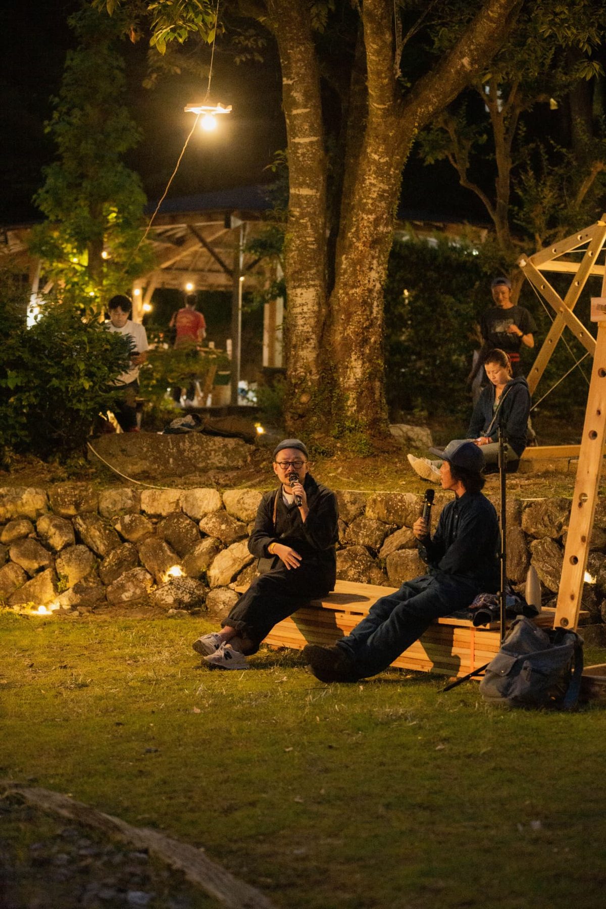 An evening talk with participants seated beneath the lit wooden canopy