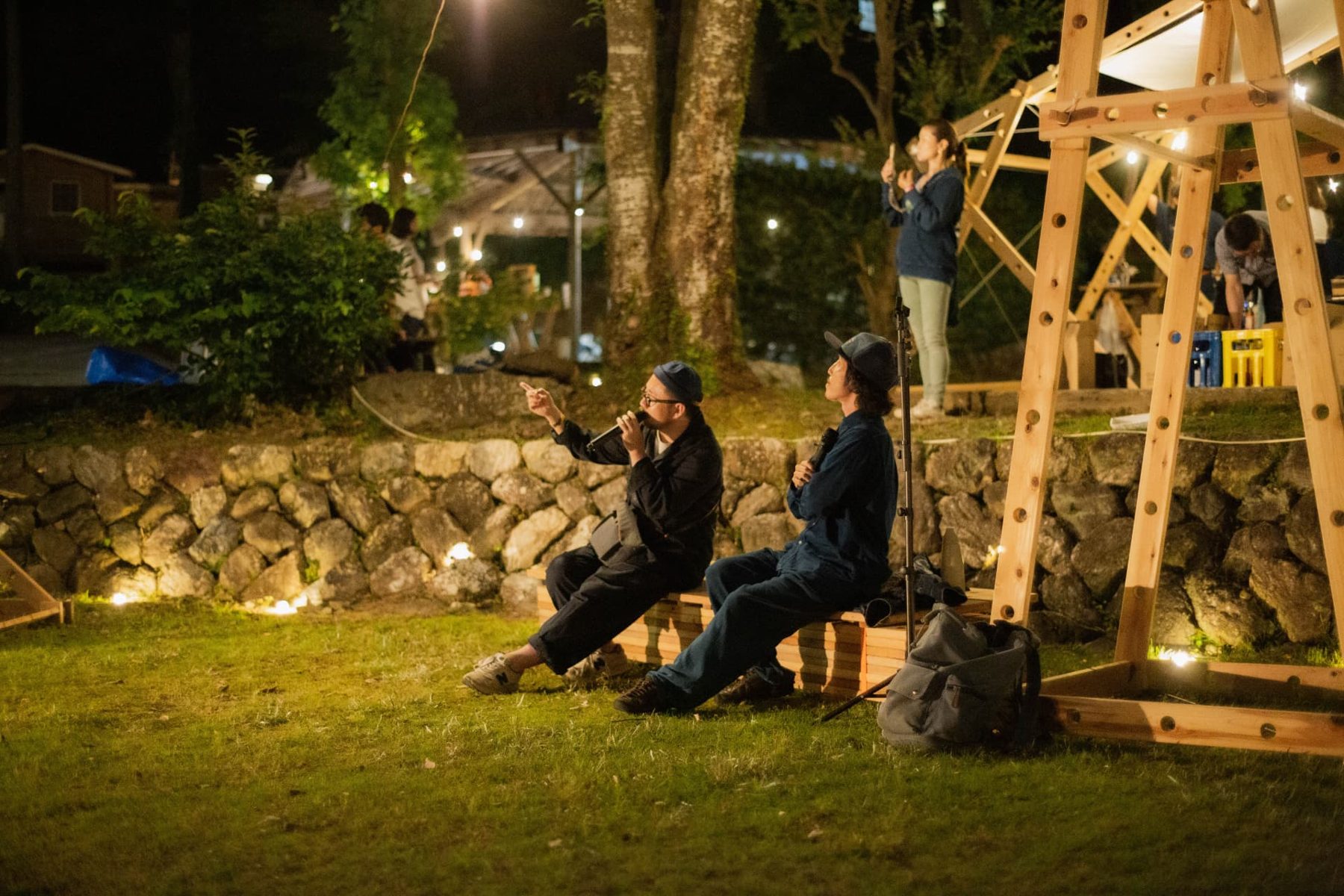 Speakers in conversation on a wooden bench at night
