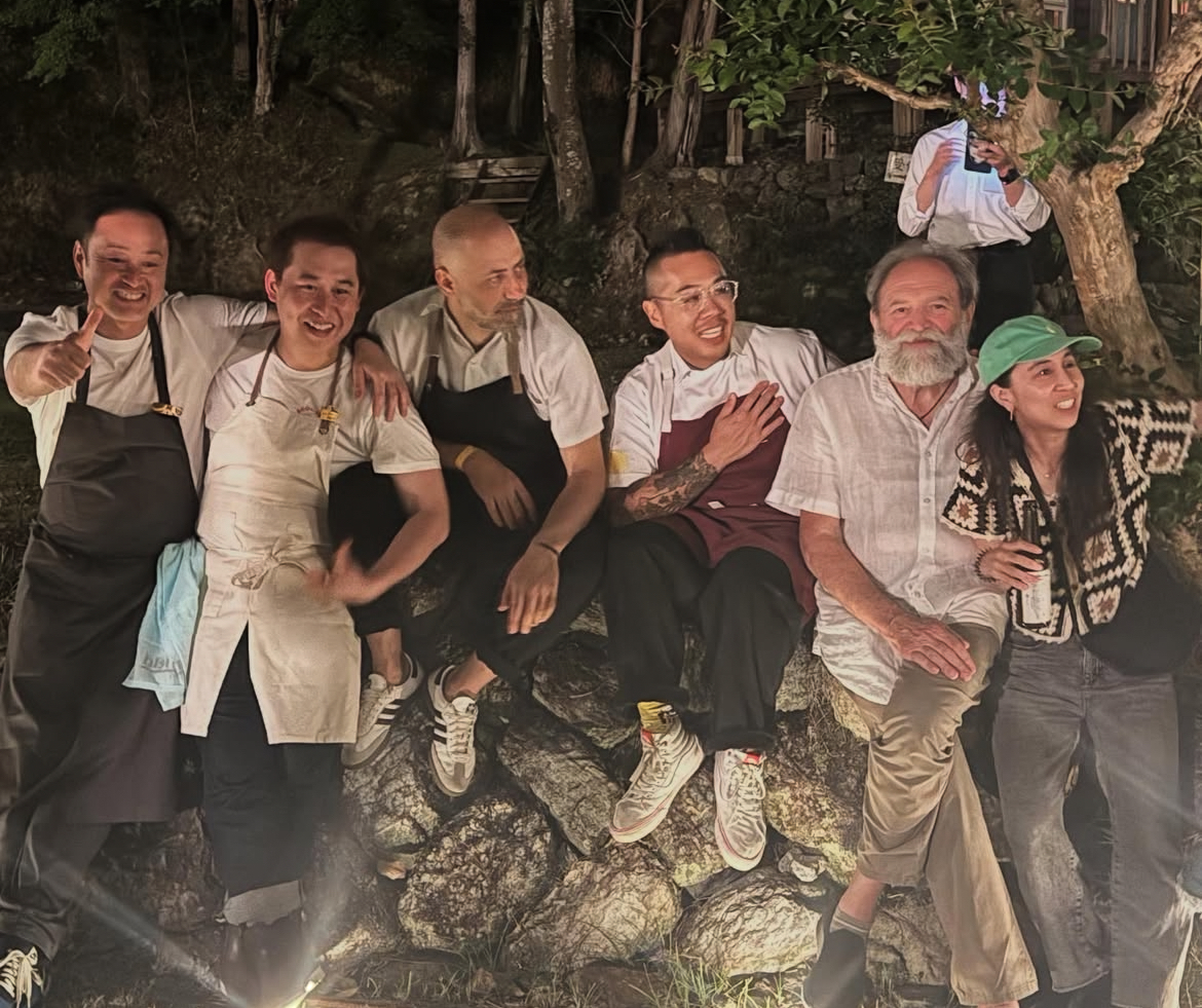 Guest chefs together at night beside a stone wall after the festival day