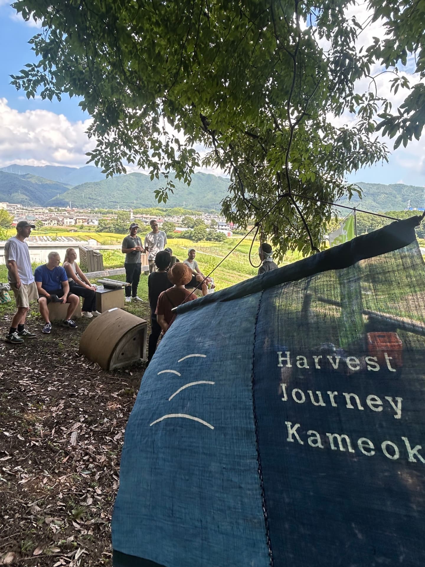 Visitors gathered under a tree at Harvest Journey Kameoka, above the valley