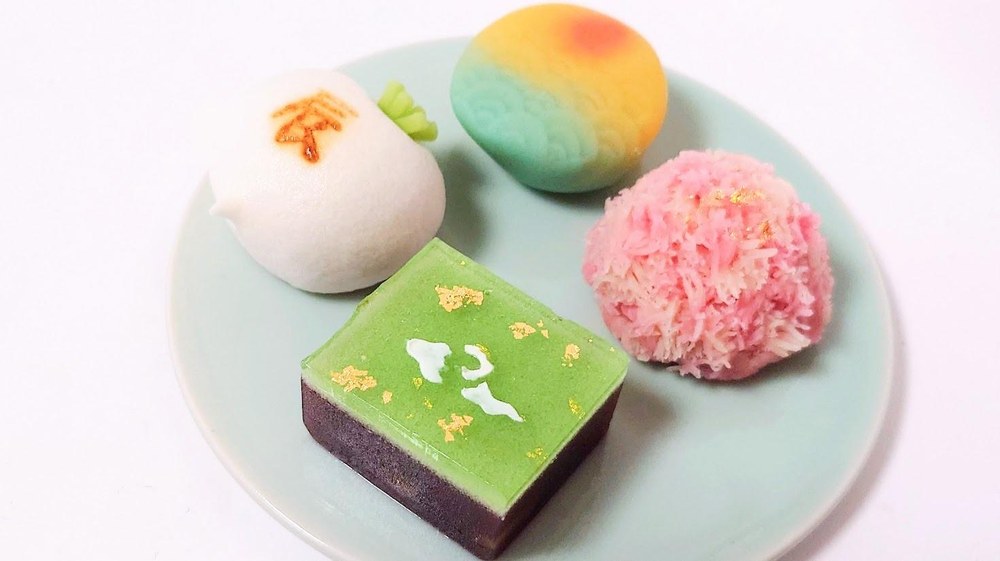 A plate of four seasonal wagashi sweets in soft pastel colours